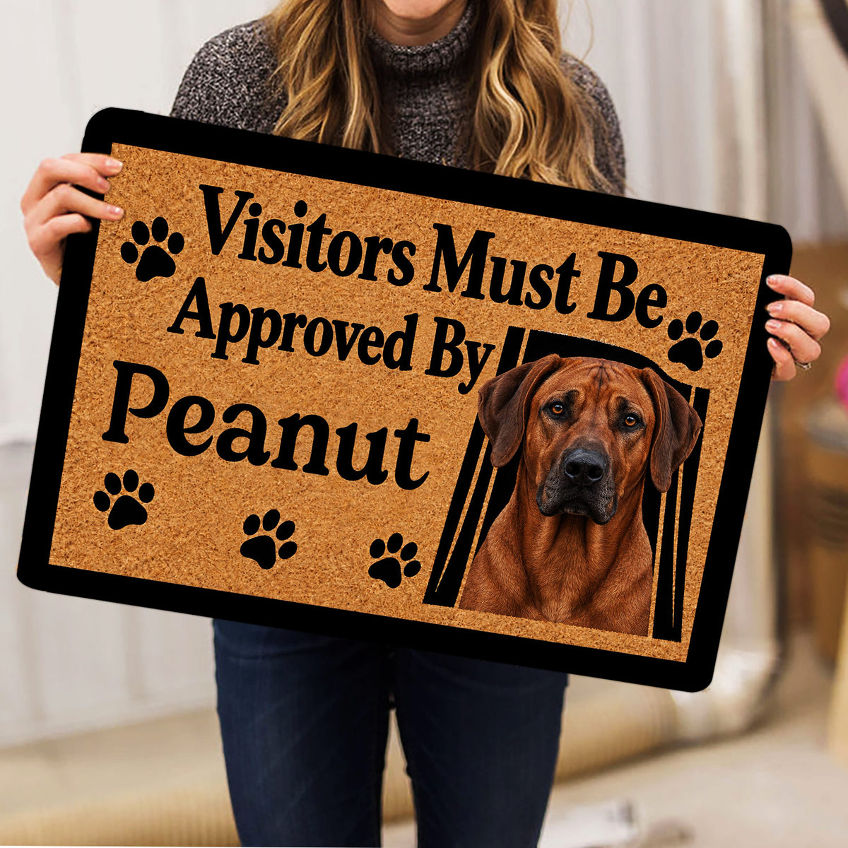 Person holding a Rhodesian Ridgeback doormat with a realistic dog portrait and paw print design