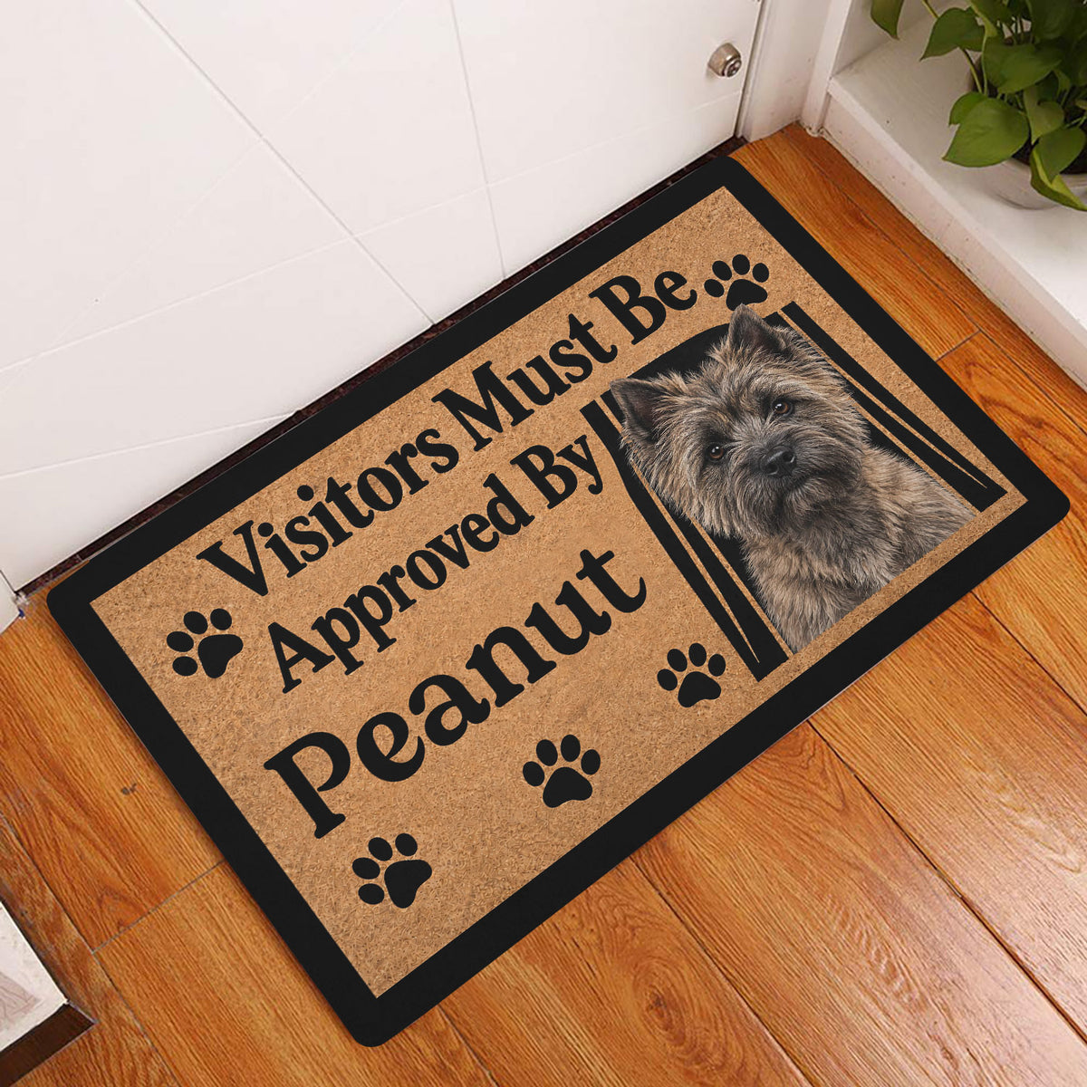 Cairn Terrier doormat displayed in a wood-floored home entryway beside a door