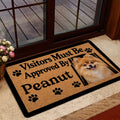 Pomeranian welcome doormat styled inside a glass doorway with flowers and a wood deck outside