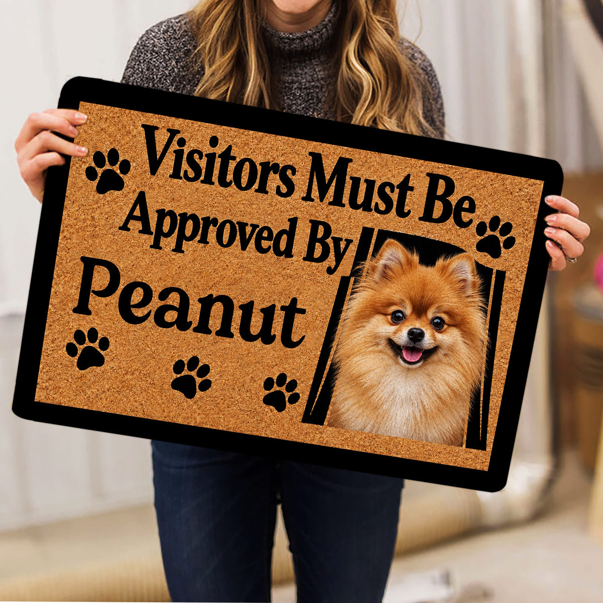 Person holding a Pomeranian doormat featuring a fluffy dog portrait, paw prints and welcome artwork