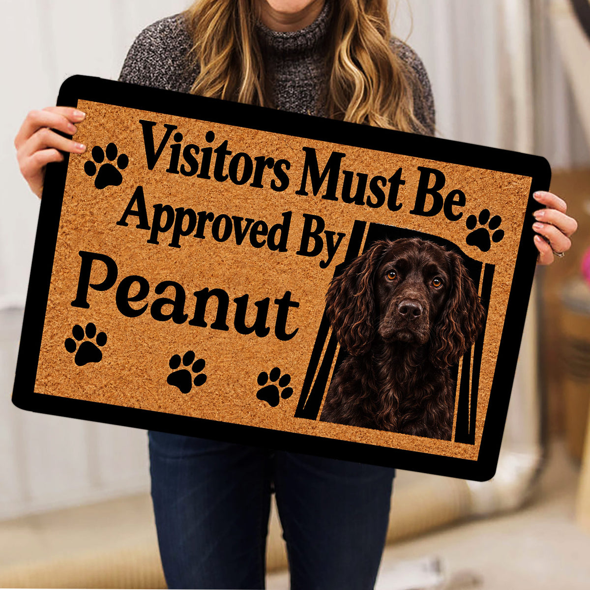 Boykin Spaniel doormat held indoors, showing the dog portrait, paw prints, and tan design