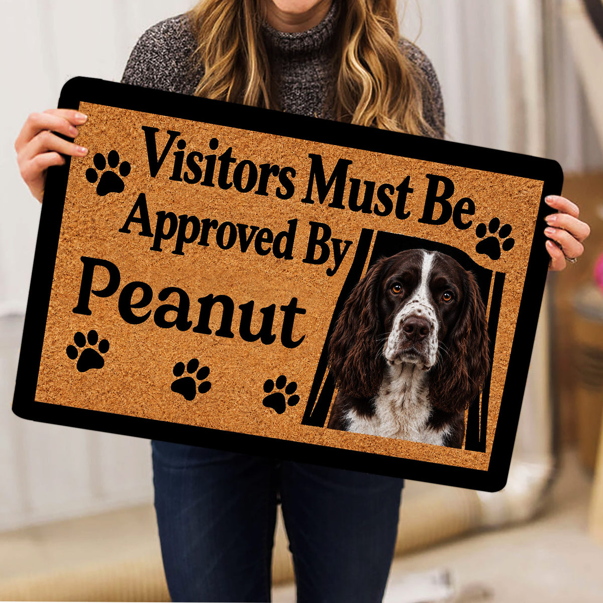 Person holding an English Springer Spaniel doormat featuring a portrait, paw prints, and welcome message