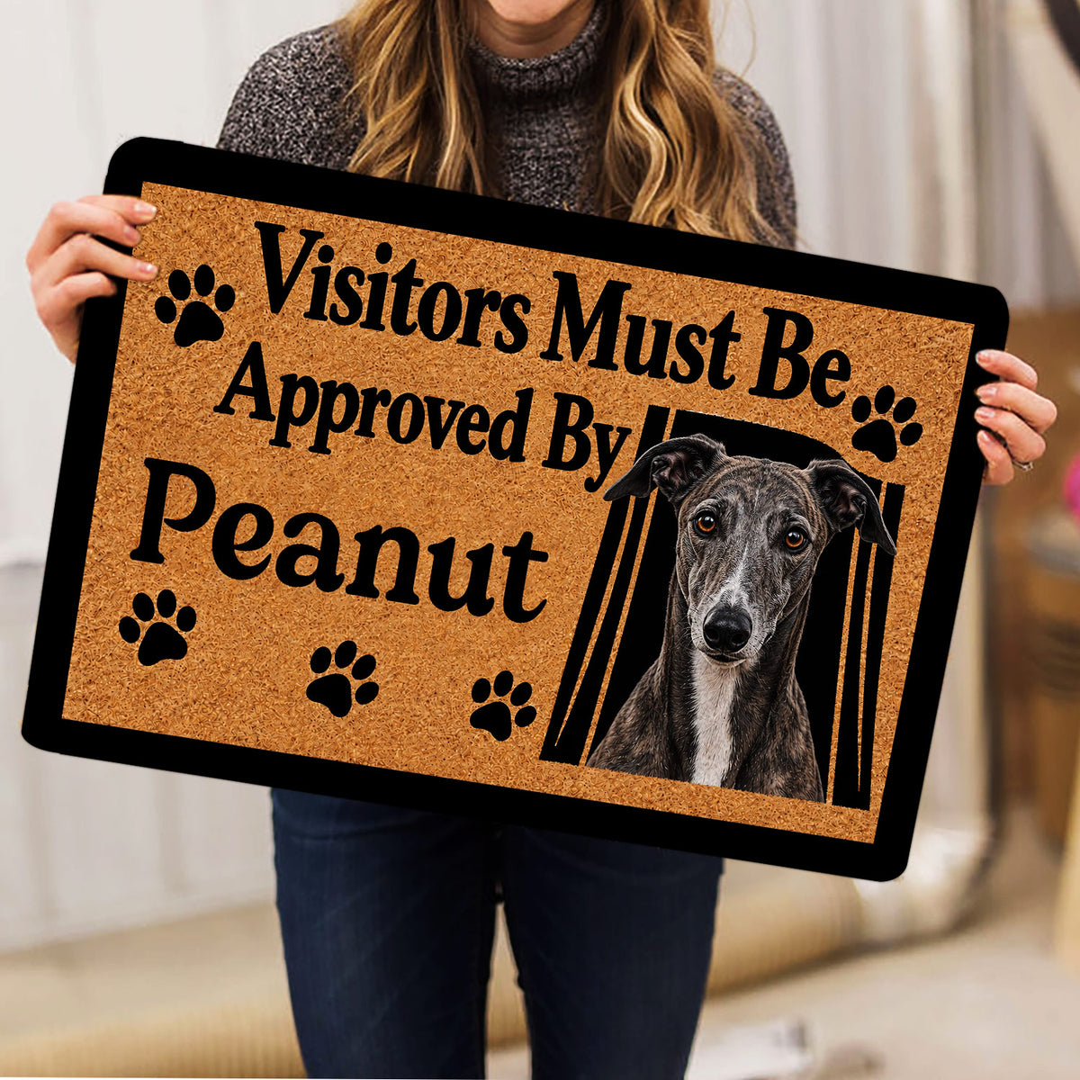 Person holding a greyhound doormat featuring a realistic portrait and playful paw-print design