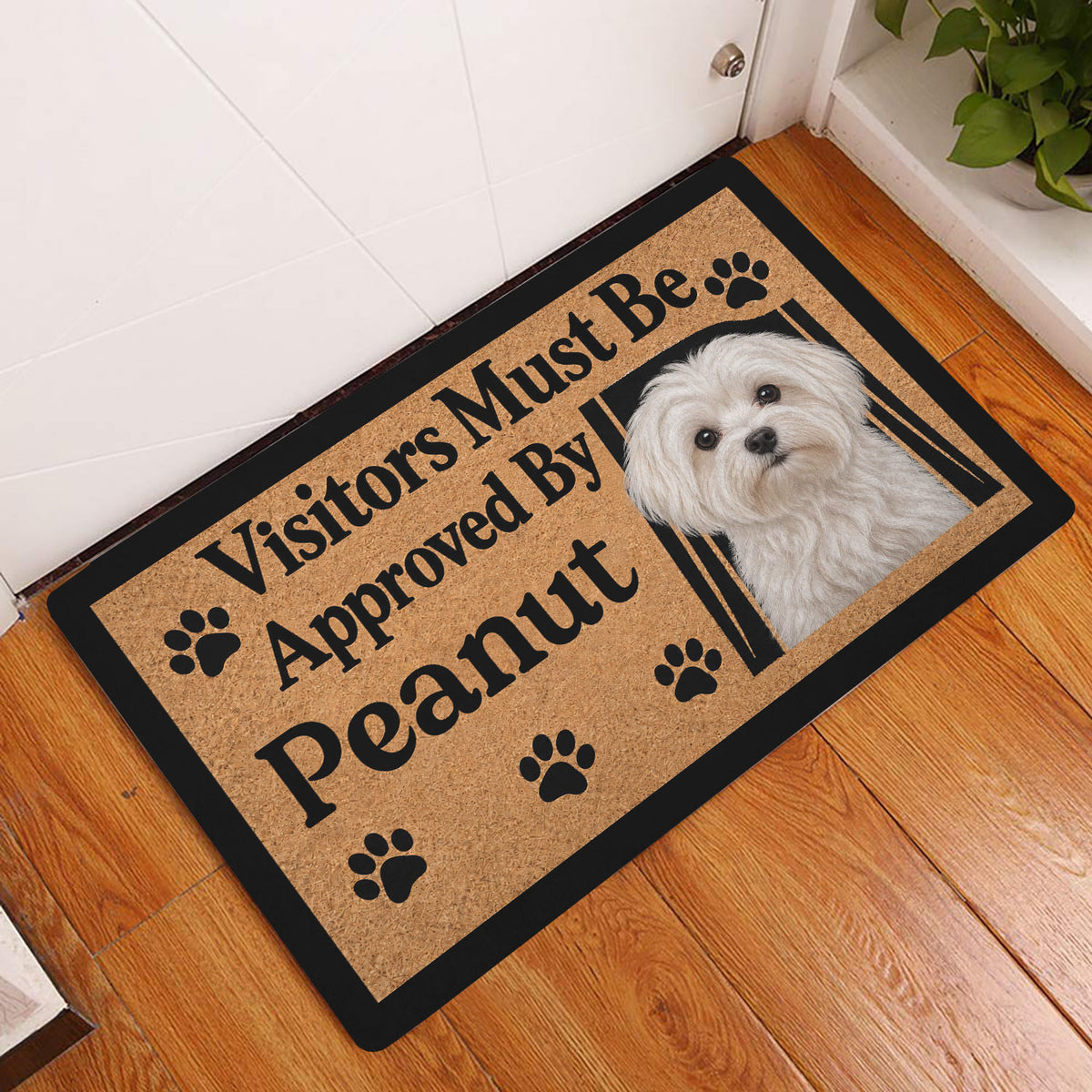 Maltese dog doormat styled by a white entry door on a wood floor in a home entryway