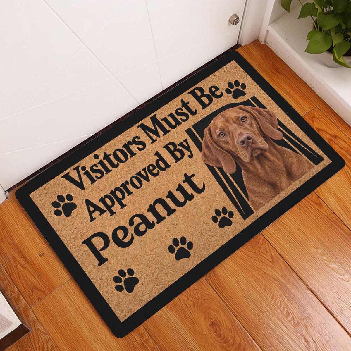 Vizsla dog entryway mat displayed beside a white door on a warm wood floor with paw print artwork