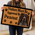 Person holding a German Shorthaired Pointer doormat showing a dog portrait, paw prints, and bold black lettering