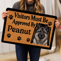 Person holding a Norwegian Elkhound doormat featuring a gray dog portrait, paw prints, and visitor lettering