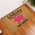 Pig-themed welcome doormat displayed by a white entry door over a warm wood floor