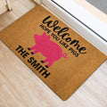 Pink pig welcome doormat styled at an interior doorway on a light wood floor