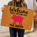Person holding a tan pig-themed welcome doormat featuring a bright pink pig illustration