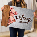 Person holding a pig-themed welcome doormat featuring playful illustrated pigs