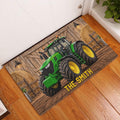 Green tractor doormat displayed on a warm wood floor near an interior doorway