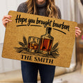 Bourbon doormat held indoors, showing bottle and whiskey glass artwork with a rustic amber palette