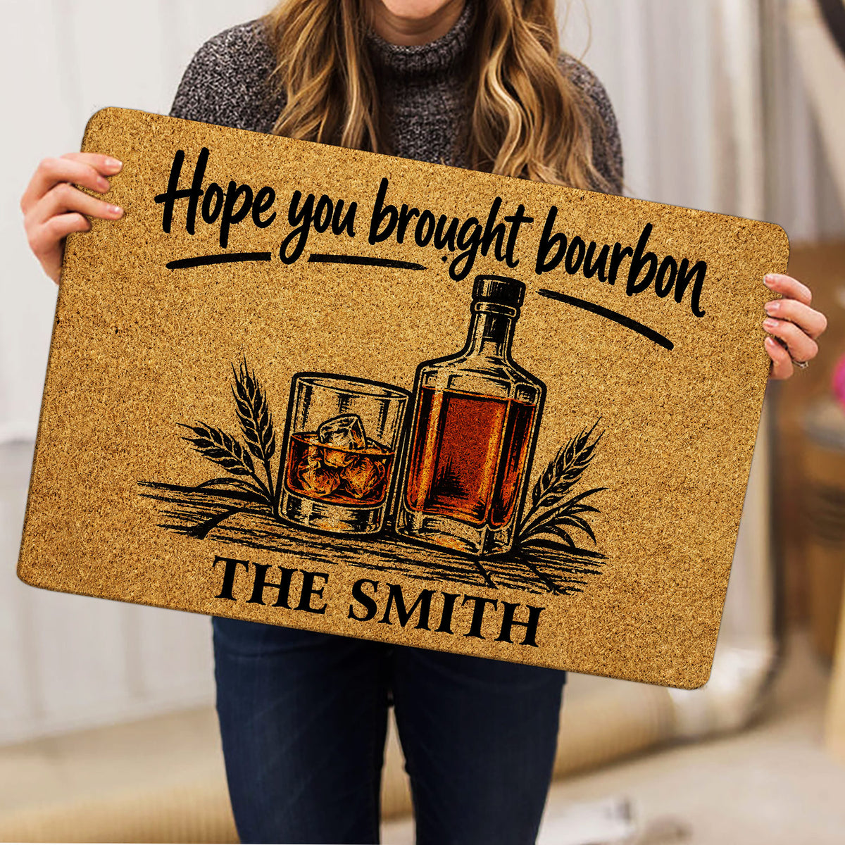 Bourbon doormat held indoors, showing bottle and whiskey glass artwork with a rustic amber palette