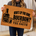 Person holding a bourbon doormat featuring a bottle, whiskey glass, and bold black typography