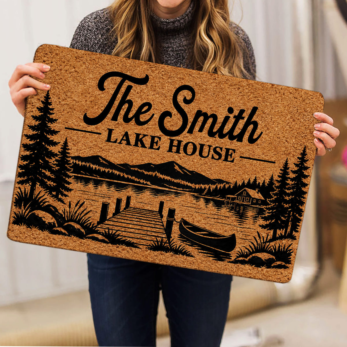Lake house doormat held indoors showing rustic mountain lake scenery, pine trees, dock, and canoe