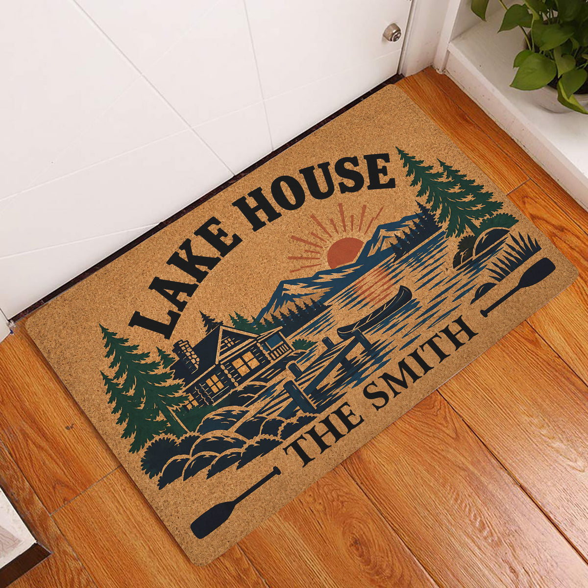 Lake house doormat displayed at an entryway on a warm wood floor with cabin and lake artwork