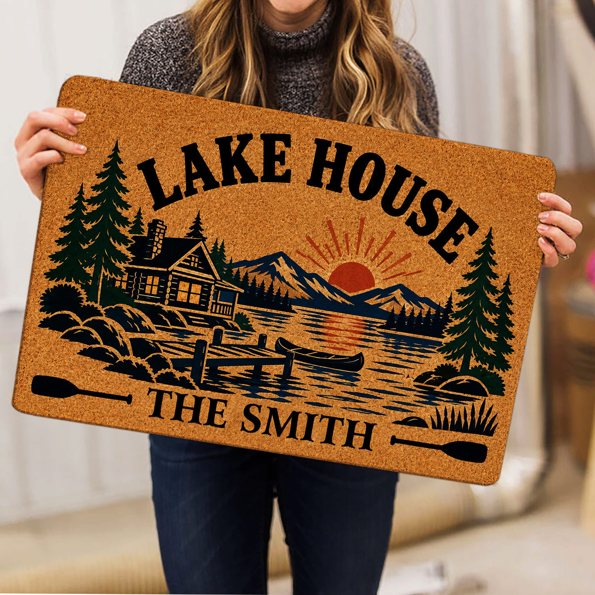 Lake house doormat held indoors, displaying a cabin, canoe, mountains and evergreen trees