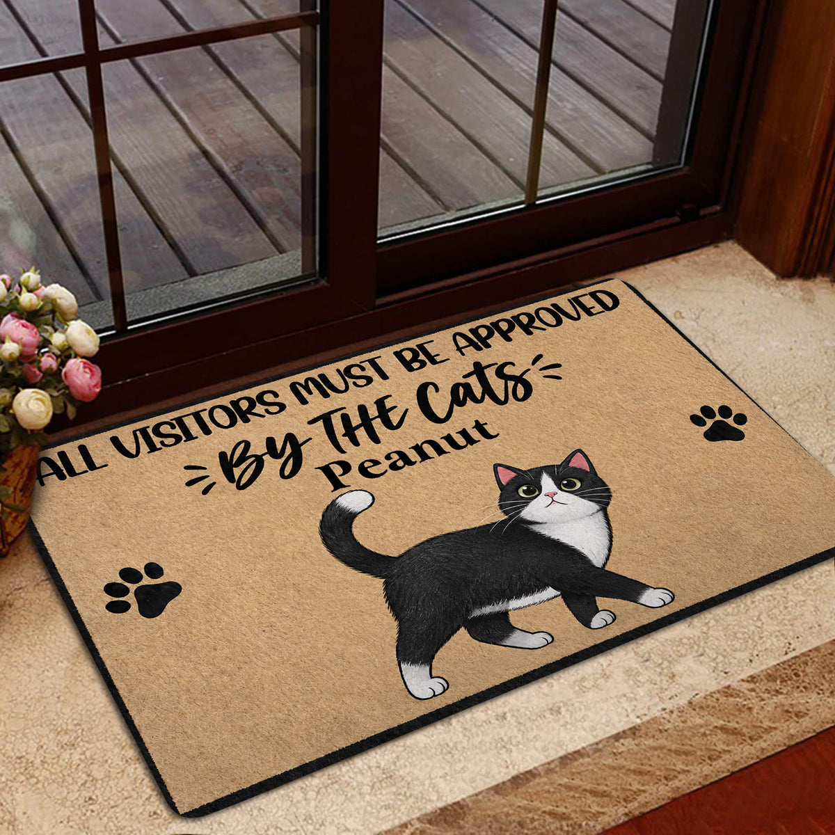Tuxedo cat doormat styled at a home entrance with glass doors, flowers and warm decor
