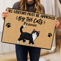 Person holding a tuxedo cat doormat featuring paw prints and a playful cat-themed message