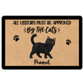Black cat doormat with paw prints and playful visitor approval message on a tan background