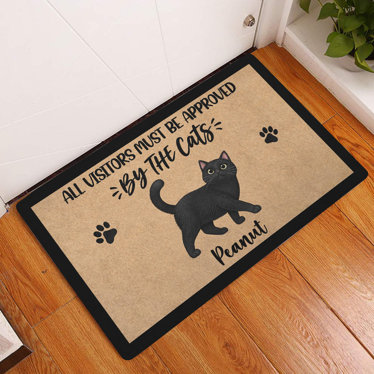 Black cat doormat displayed in a bright entryway beside a white door and wood floor