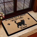 Black cat doormat styled inside a home entrance near a glass door and floral arrangement