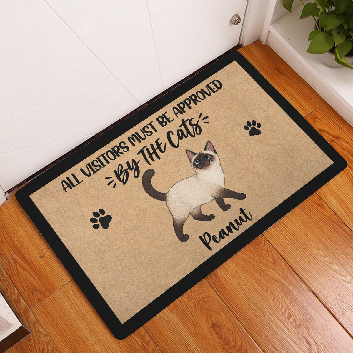 Siamese cat entryway mat displayed beside a white door on a wood floor