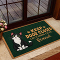 Tuxedo cat doormat displayed at a home entrance with playful paw print artwork and warm tan accents
