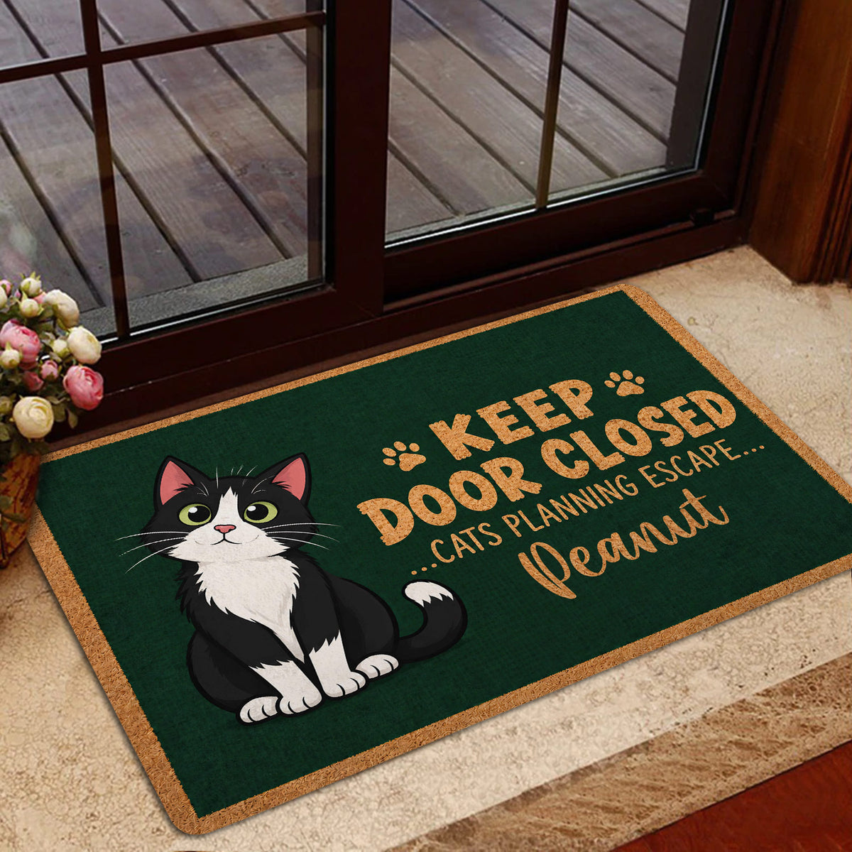 Tuxedo cat doormat displayed at a home entrance with playful paw print artwork and warm tan accents
