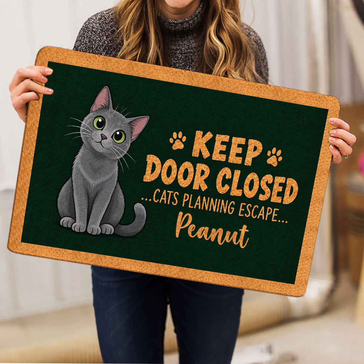 Person holding a Russian Blue cat doormat featuring a gray cat and paw print design