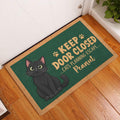 Black cat entryway doormat displayed beside a white door on a warm wood floor