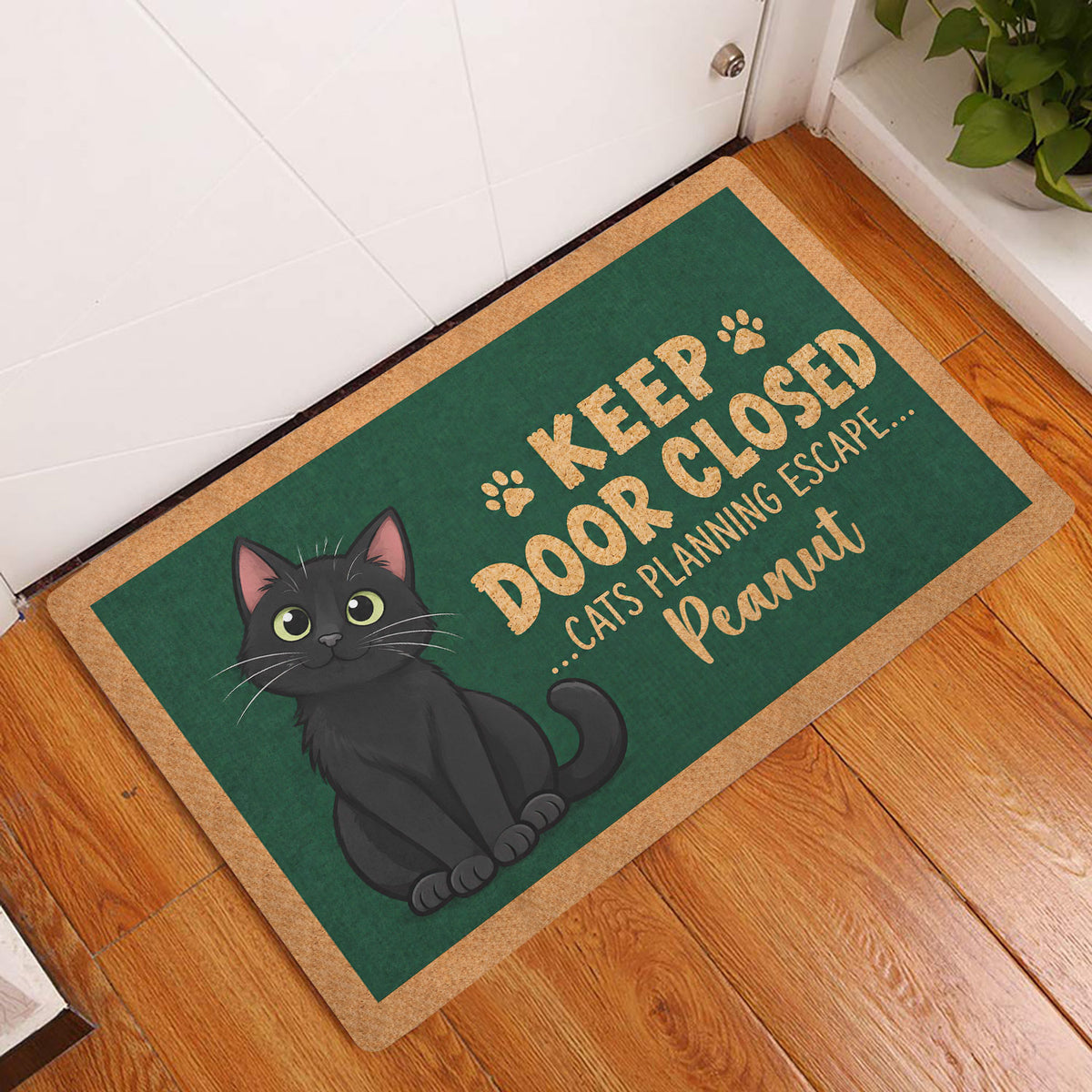 Black cat entryway doormat displayed beside a white door on a warm wood floor