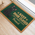 Black cat door mat with green artwork and playful escape message at an indoor entrance