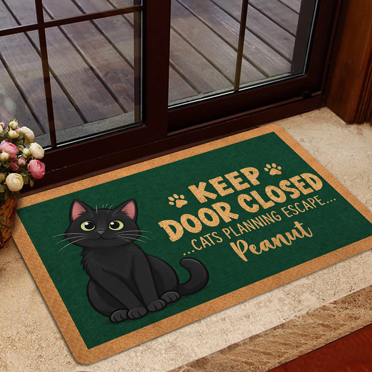 Black cat front door mat styled in a home entryway with glass doors and wood decking outside