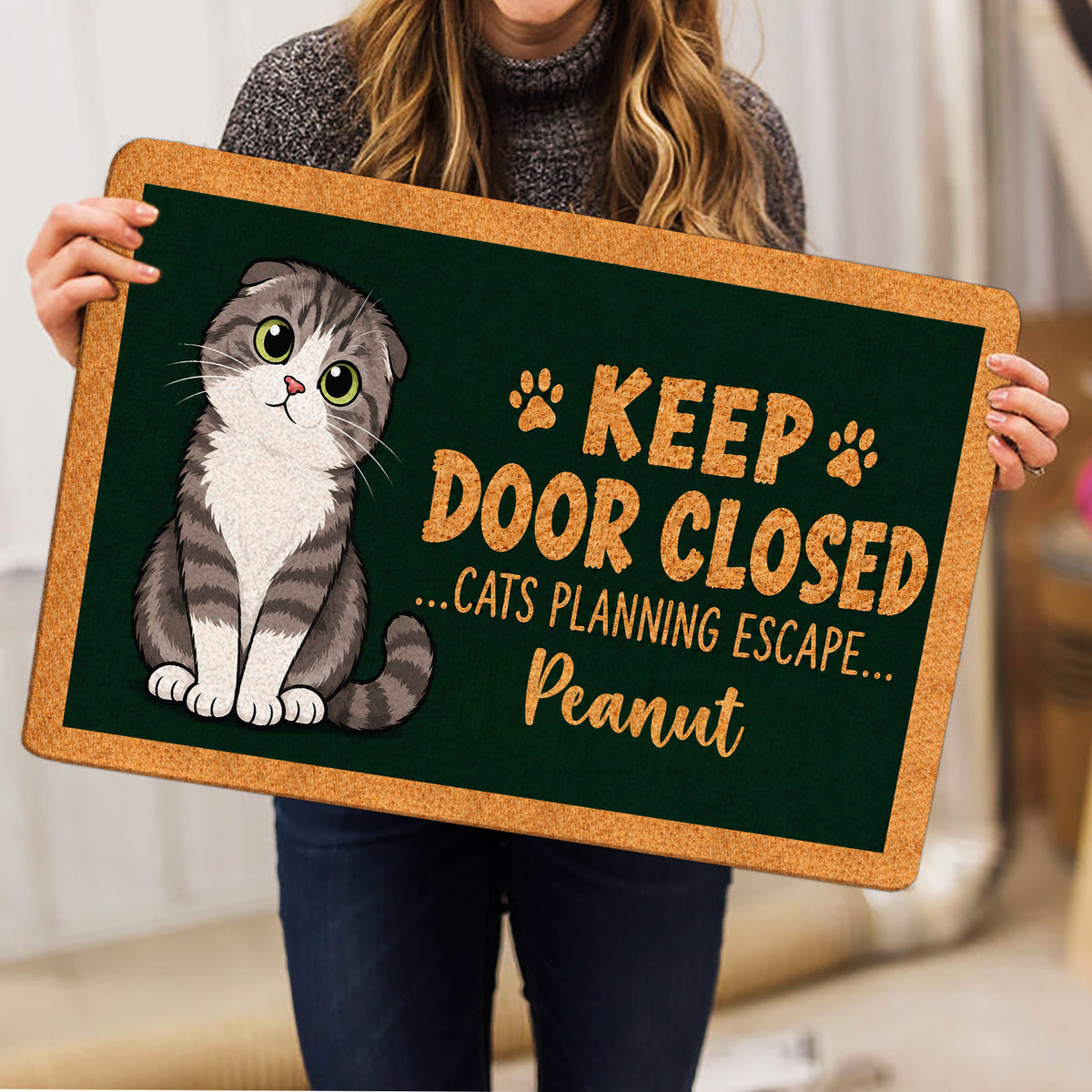 Cat lover doormat shown in a home setting with an illustrated Scottish Fold cat and green artwork