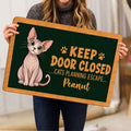 Person holding a Sphynx cat doormat featuring playful paw prints and escape-themed artwork