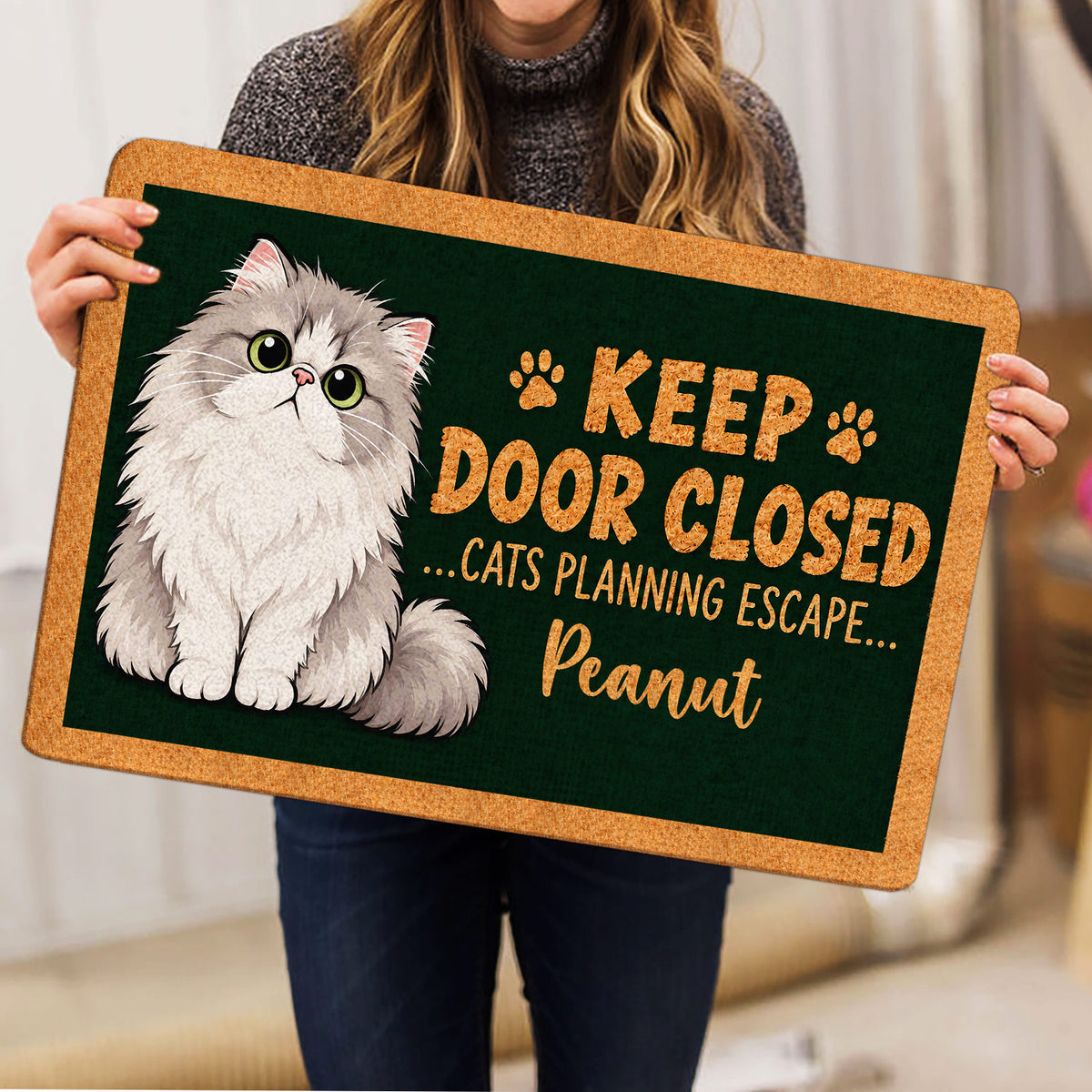 Person holding a Persian cat doormat featuring a fluffy cat and playful entryway artwork