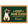 Siamese cat doormat with blue eyes, paw accents, and a playful door warning on a green background
