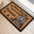Gray Weimaraner entryway mat with paw prints and bold black lettering near a doorway