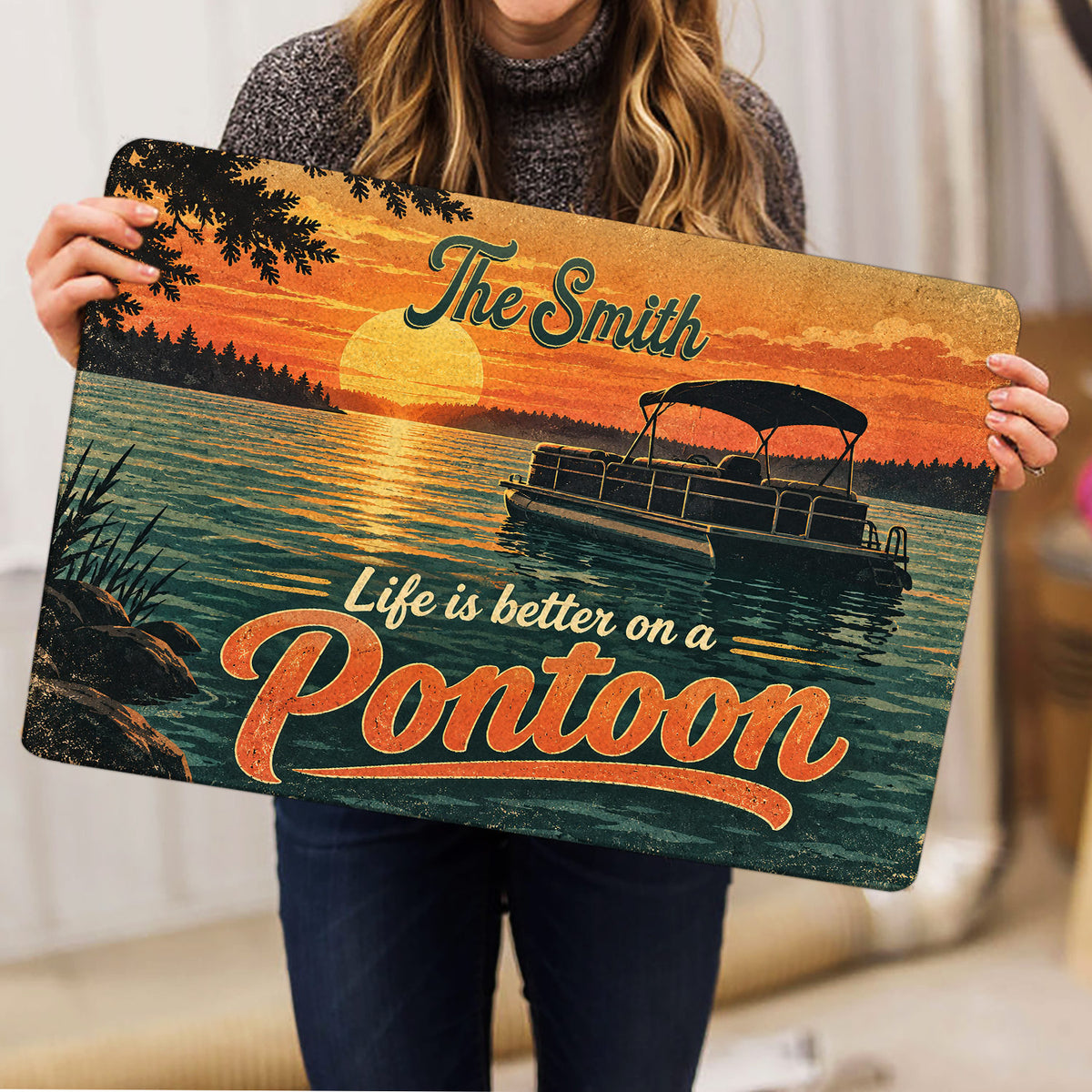 Pontoon doormat held indoors showing a sunset lake illustration, pontoon boat, and bold decorative lettering
