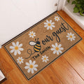 Bee and daisy doormat displayed at a front door on warm wood flooring in an entryway