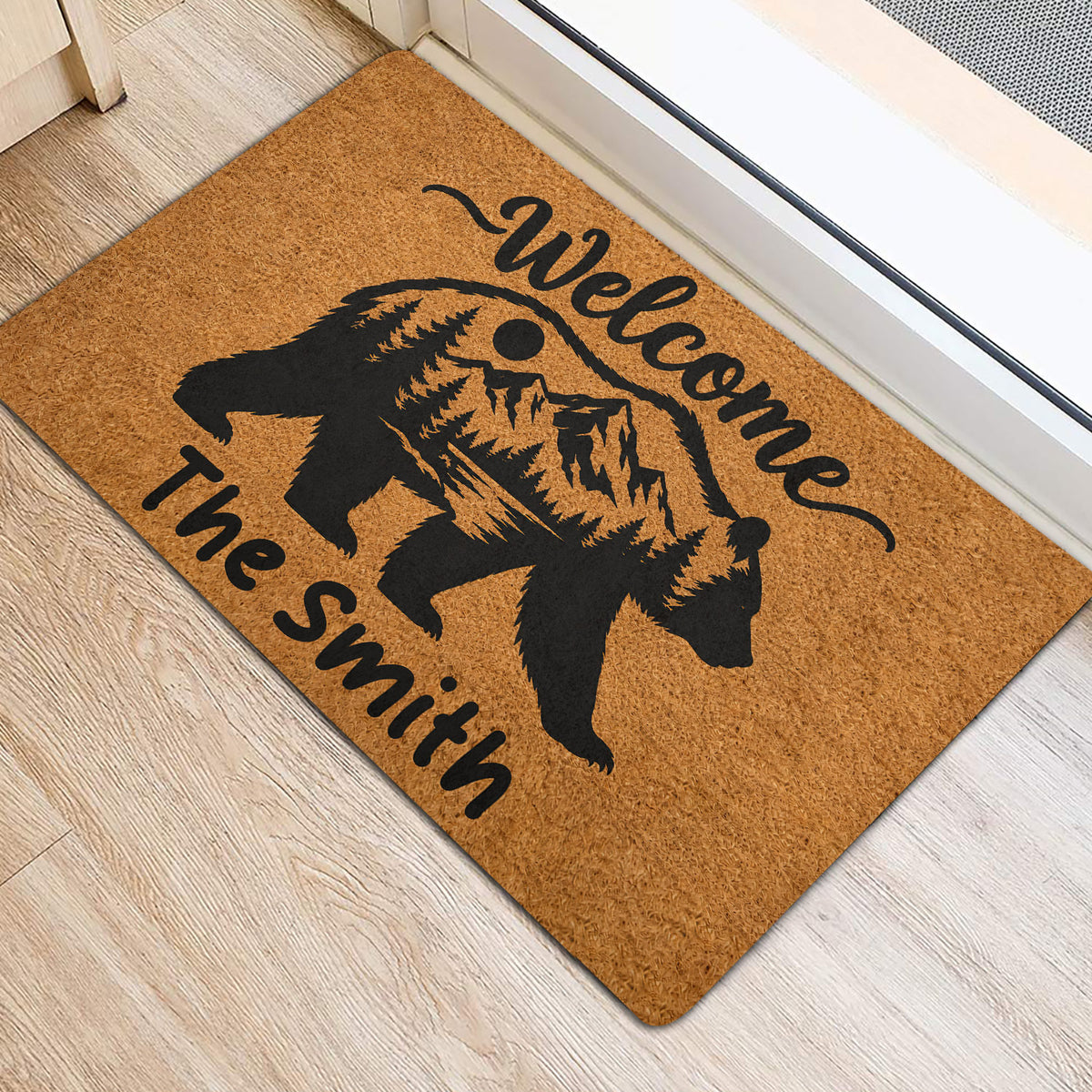 Bear and mountain welcome doormat positioned near an interior doorway on a light wood floor