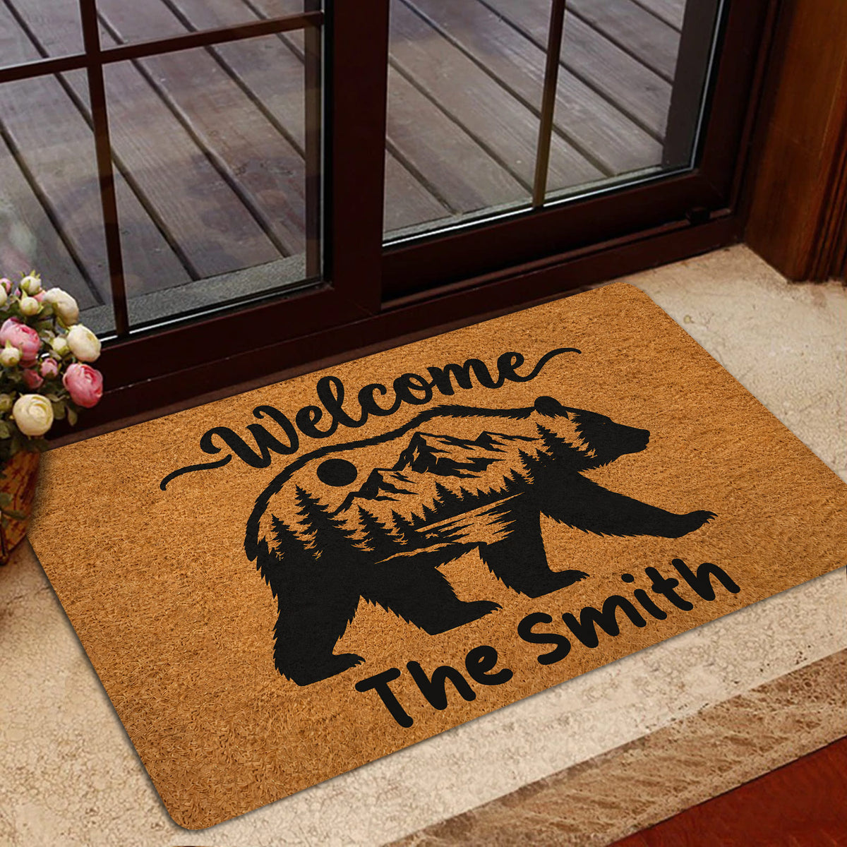 Bear silhouette entryway mat styled beside a glass door with a wood deck and home decor setting