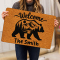 Person holding a bear welcome doormat featuring a mountain landscape and forest silhouette design