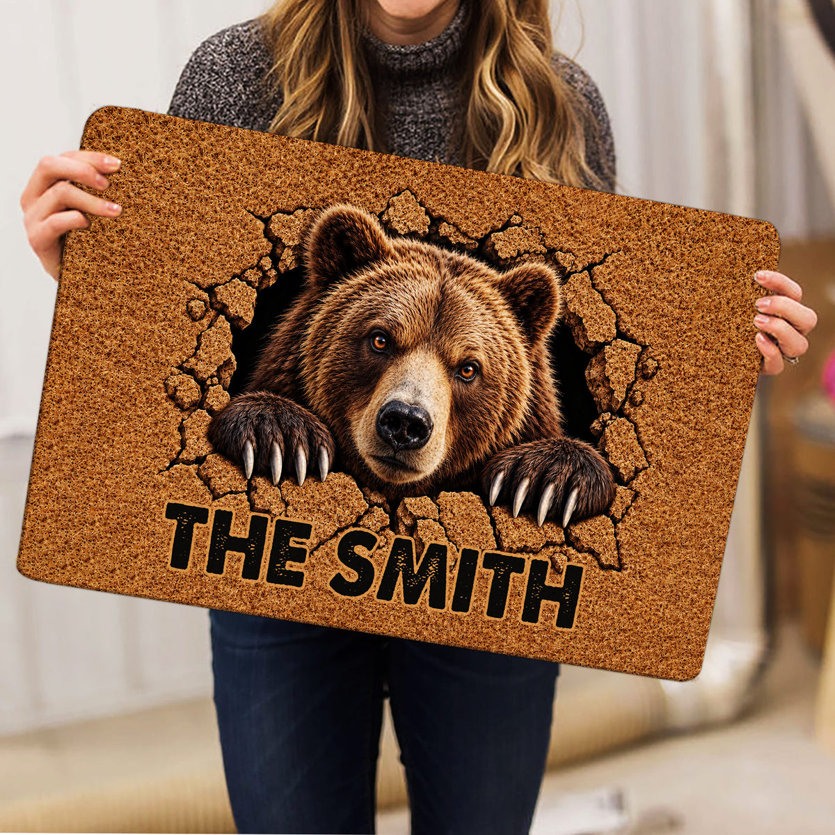 Person holding a bear doormat featuring realistic wildlife artwork, textured brown tones, and bold lettering