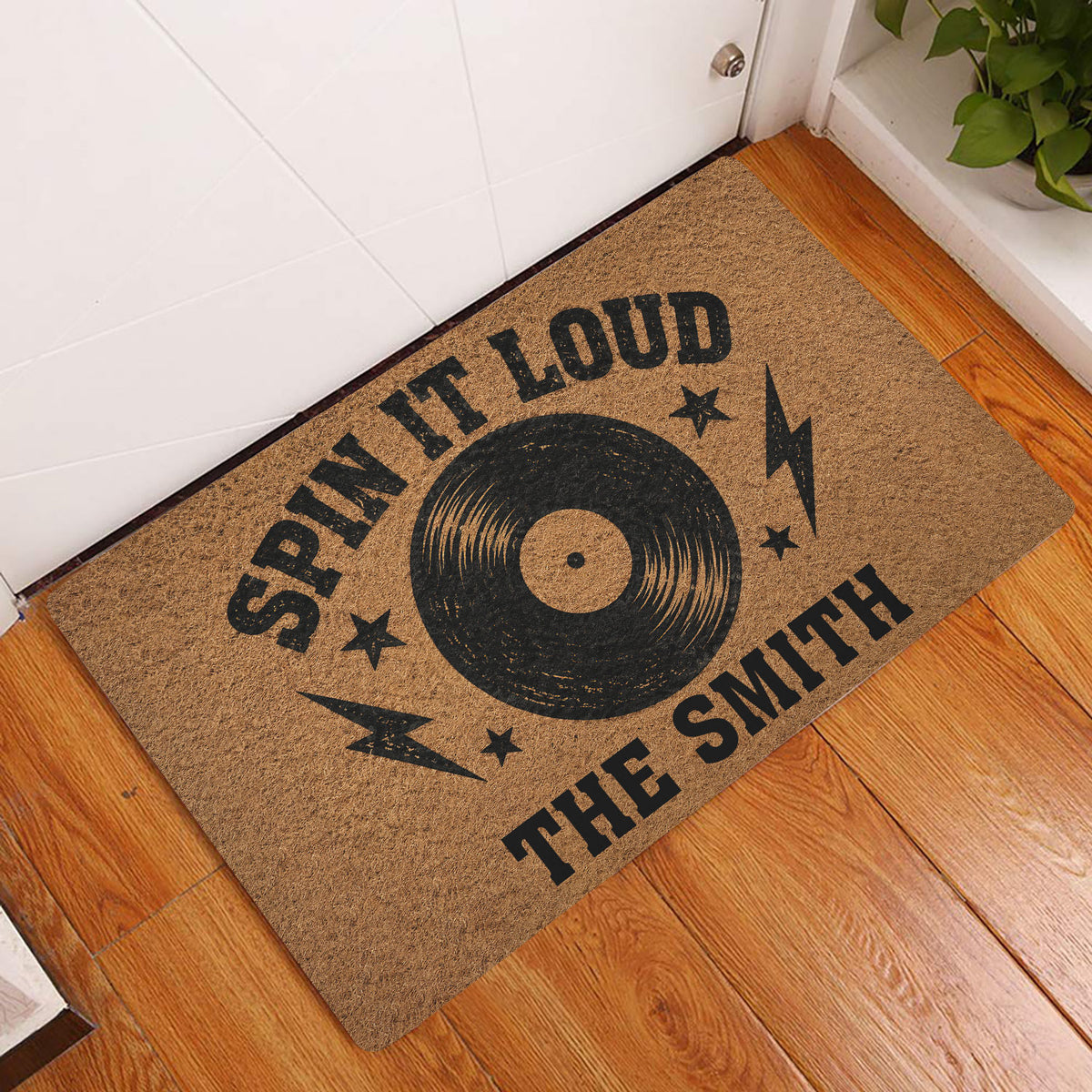 Rock and roll vinyl record doormat displayed at an indoor entryway beside a white door