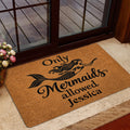 Mermaid welcome doormat styled inside a glass doorway beside flowers and a layered rug