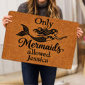 Woman holding a mermaid-themed doormat featuring a flowing-haired mermaid and tail illustration