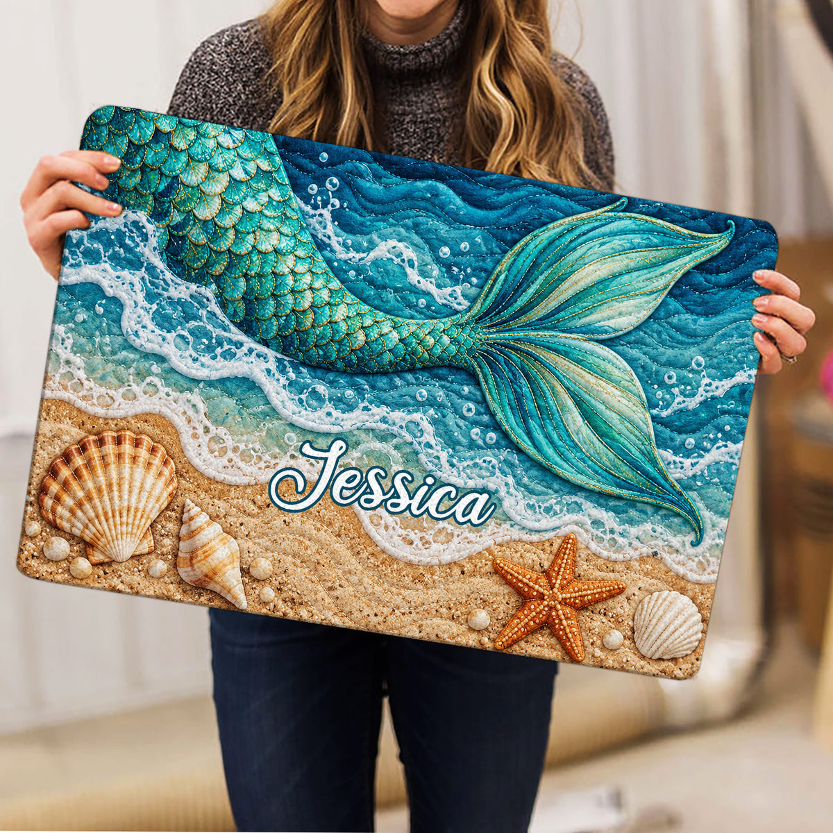 Mermaid doormat held indoors, showing a colorful ocean beach scene with a detailed turquoise tail